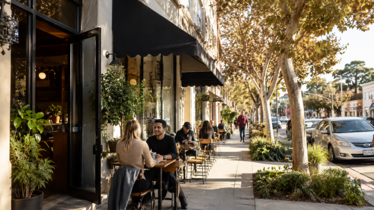 Tree-lined Modesto street with sidewalk dining, local storefronts, and pedestrians